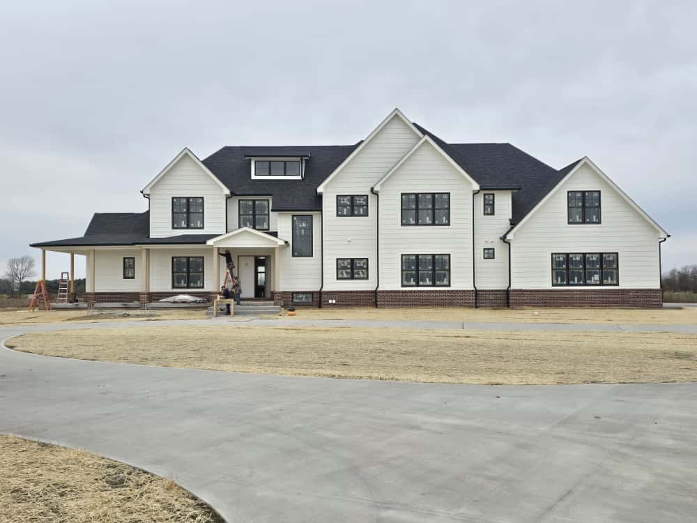 A two-story home with white siding and a dark shingle roof