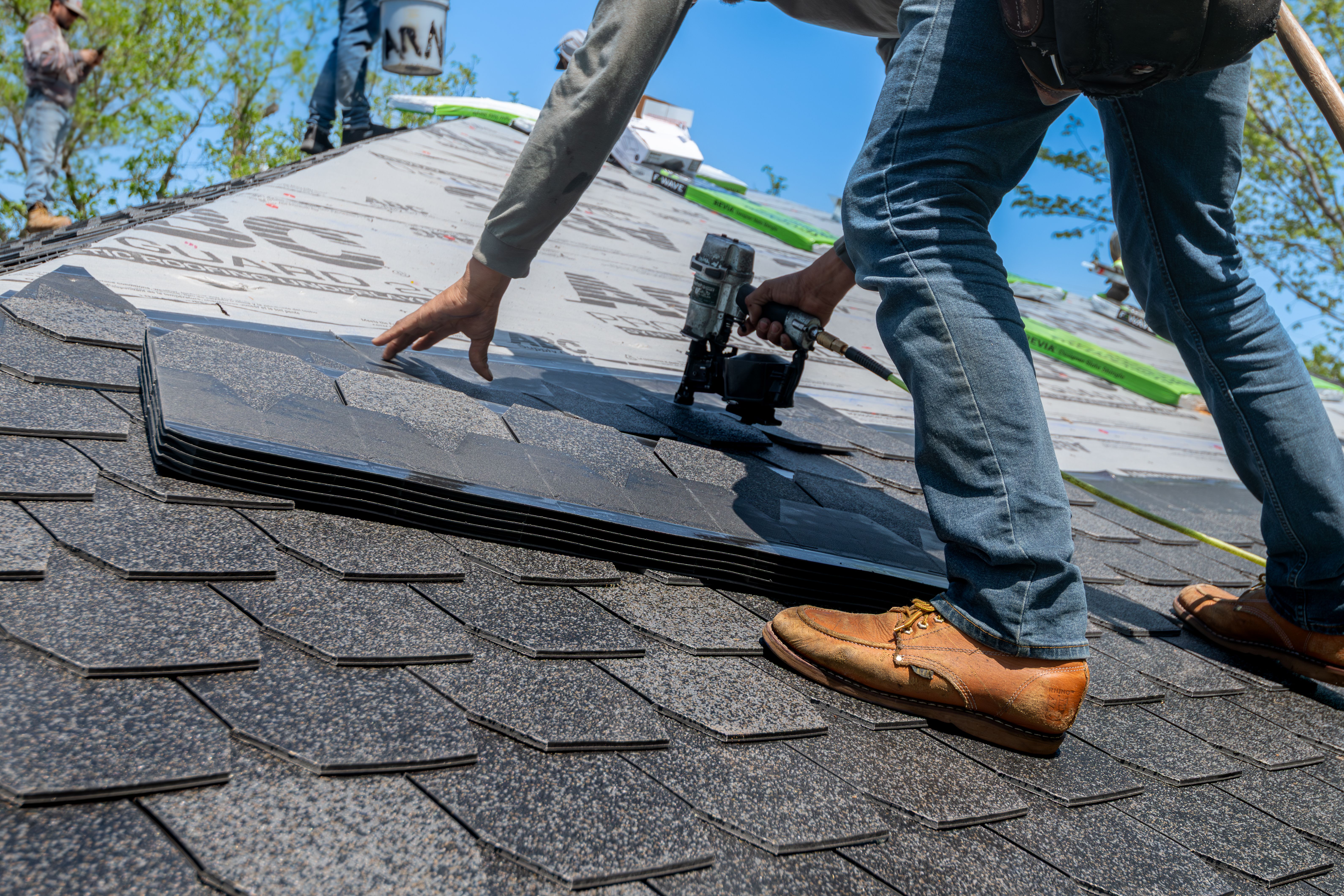 Roofers installing asphalt shingles on a residential roof